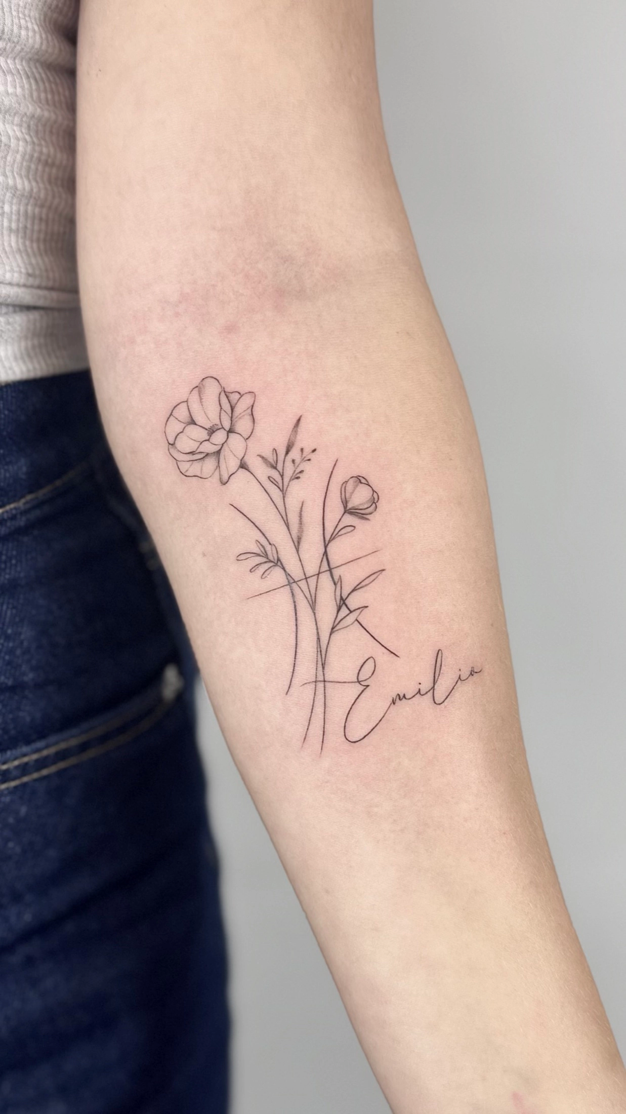 Florales Fineline Tattoo mit Schriftzug von Joshua Téclaire, Dorsten